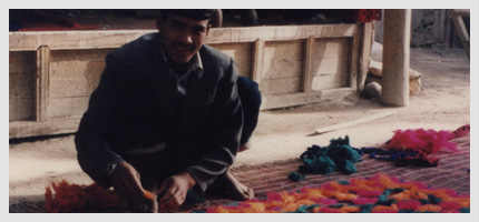 Young man making a felt rug in the courtyard of his home